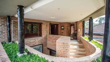 A covered outdoor area with brick walls, a central brick column, and a staircase leading to an upper level.