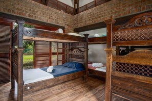 A bunk bed room with wooden flooring and a brick wall.