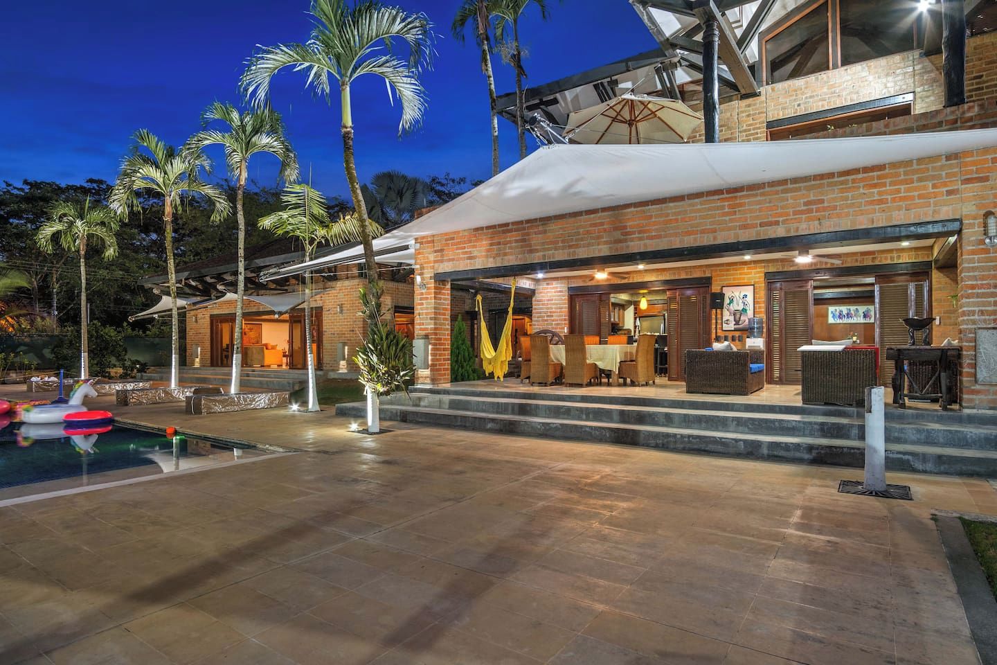 A hotel with a pool, outdoor seating, and palm trees.