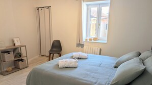 Et soveværelse med seng, stol, vindue og radiator.