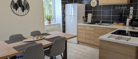 A modern kitchen with a built-in oven, a coffee machine, and a clock on the wall.