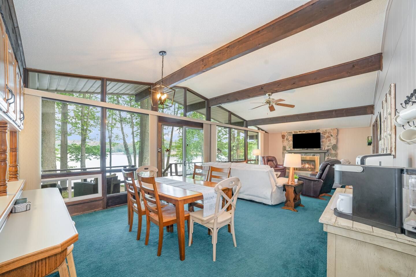 A spacious living area with a dining table, chairs, a fireplace, and a television.