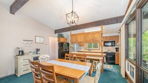 A kitchen with wooden cabinets, a dining table with chairs, and a hanging light fixture. - Lodge No Complaints - Harrison (Harrison)