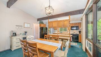 A kitchen with wooden cabinets, a dining table with chairs, and a hanging light fixture.