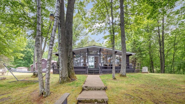 A lodge with a covered deck, a concrete pathway leading to it, and a hammock in the foreground. - Lodge No Complaints - Harrison (Harrison)