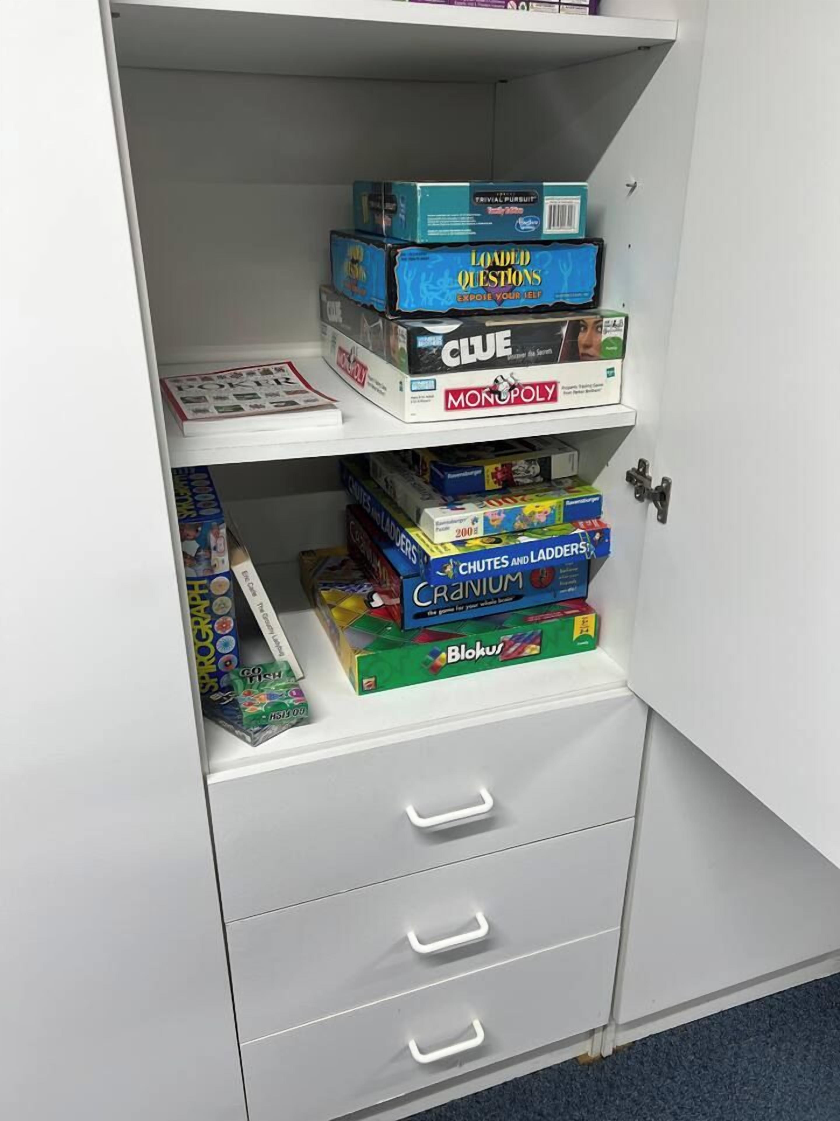 Un mueble con varios cajones y estantes que guardan diferentes juegos de mesa.