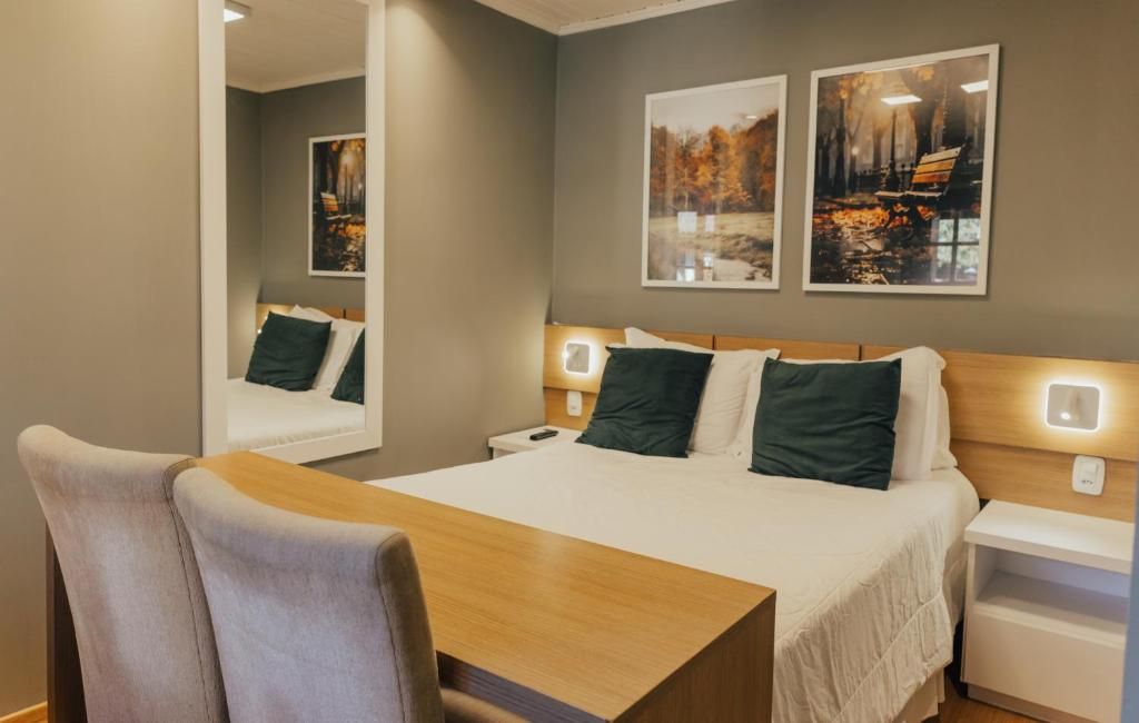 Una habitación de hotel con una cama, mesitas de noche, un escritorio y sillas.