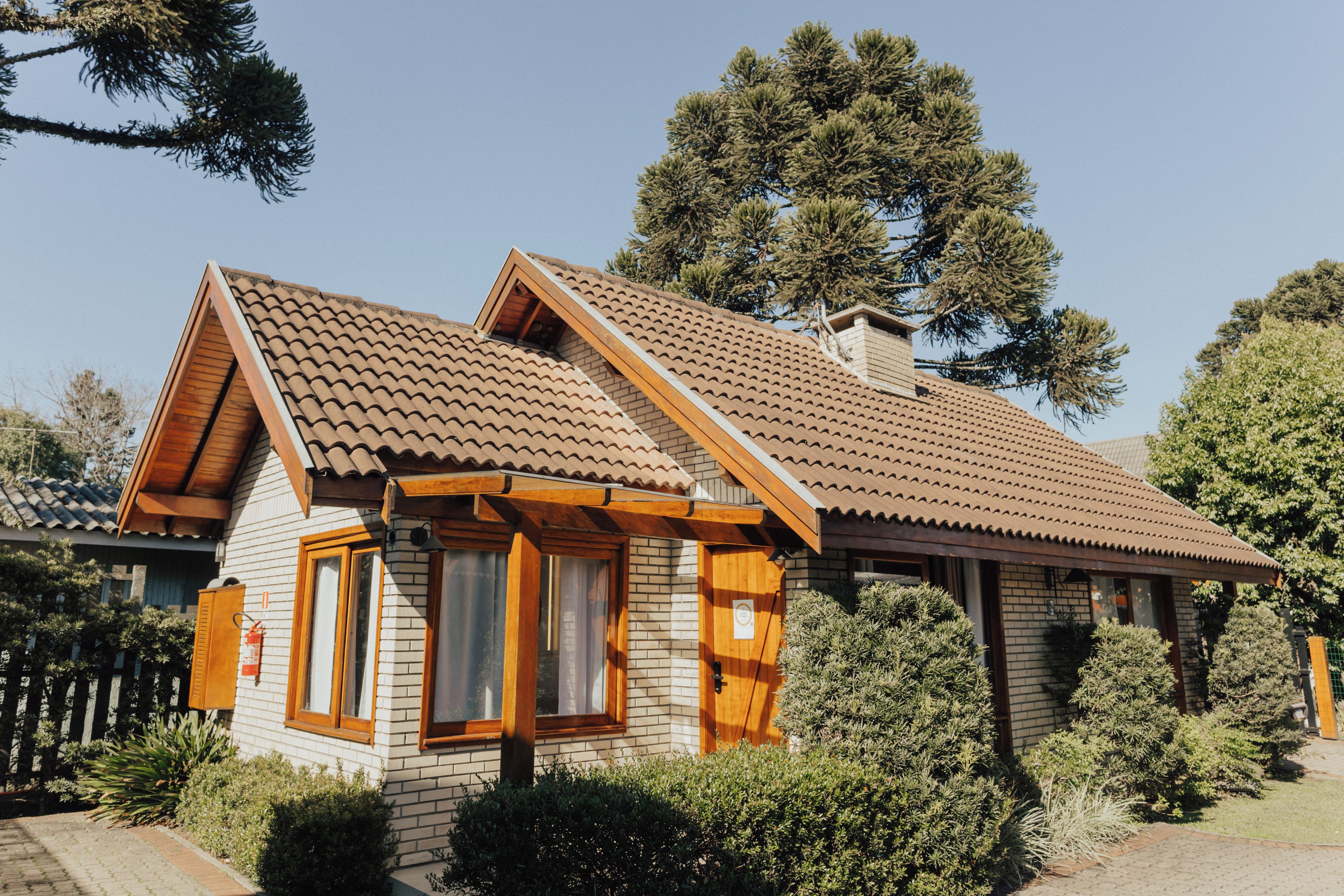 Una casa de dos pisos con techo a dos aguas, fachada de madera y chimenea de ladrillo.