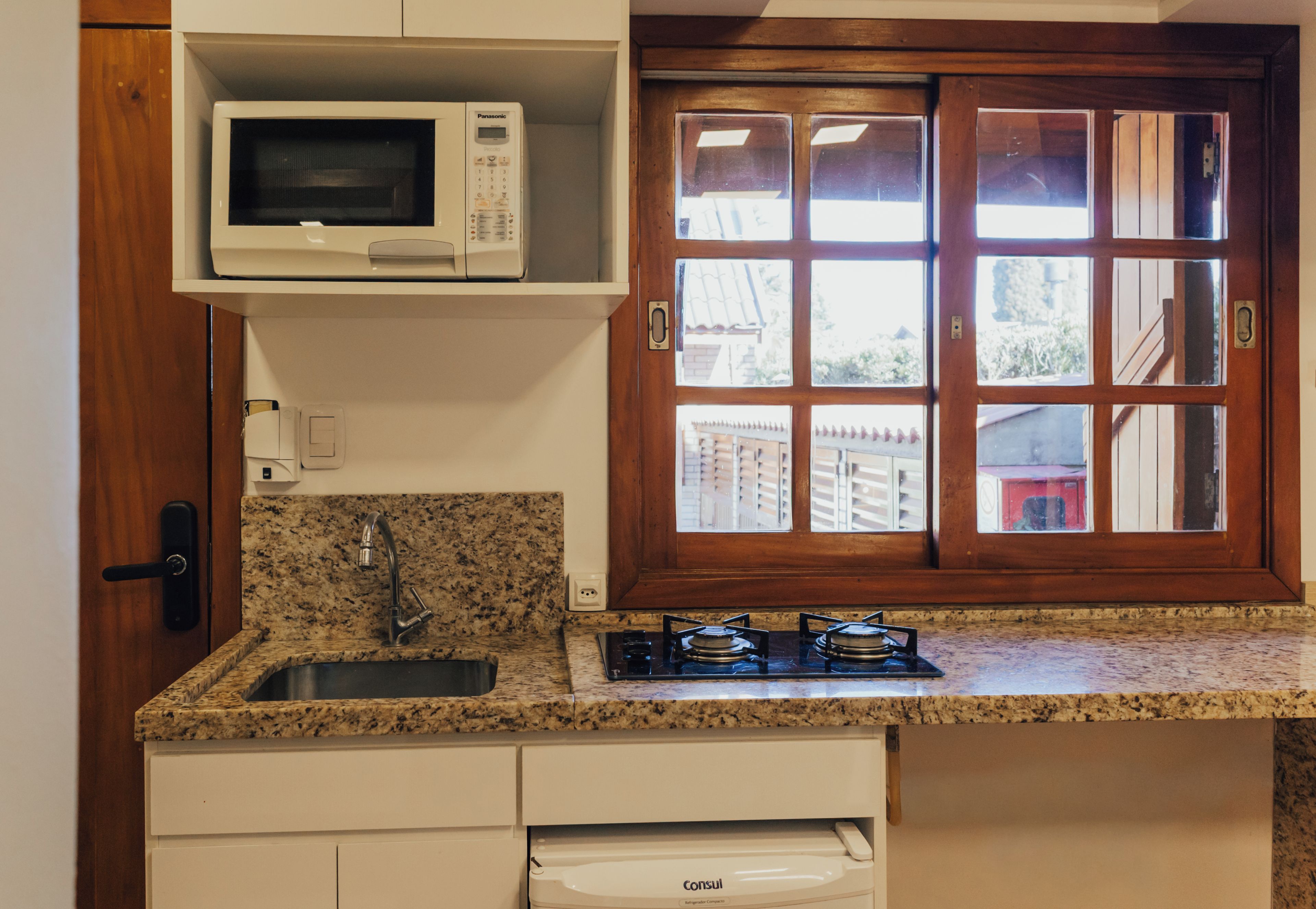 A kitchen with a built-in microwave, a gas stove, a sink, and a window with a view of the outside.