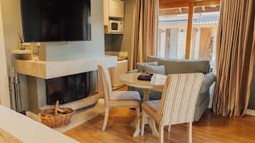 Ein modernes Wohnzimmer mit Flachbildfernseher, Kamin, Esstisch mit Stühlen und einer Couch.