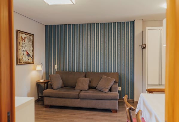 Una sala de estar con un sofá, una lámpara y una pared con rayas verticales.