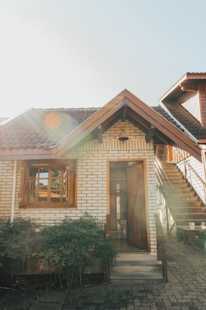 A two-story house with a brick facade, a wooden door, and a staircase leading to the upper level. - Belo Destino (Gramado)