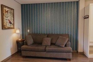 Una habitación con sofá, lámpara y pared a rayas.