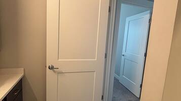 A hallway with a closed door, a wooden floor, and a carpeted entrance.