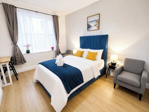 Quarto de hotel com cama, cadeira, mesa e um quadro na parede.