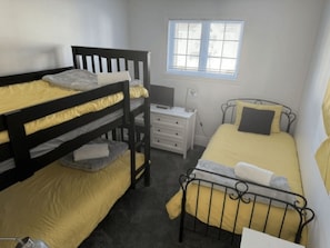A room with two bunk beds, a single bed, a bedside table, a lamp, and a window. - 3 bedrooms with heated pool (summer) Walk to slopes (Saint-Sauveur)
