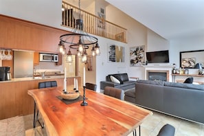 A modern living space with a wooden dining table, a sofa, a fireplace, and a TV. - 3 bedrooms with heated pool (summer) Walk to slopes (Saint-Sauveur)