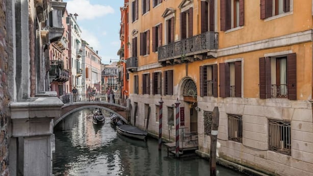 Un canal bordé de bâtiments des deux côtés, un pont et des bateaux.