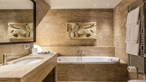 Une salle de bain avec deux lavabos, une baignoire et un grand miroir.