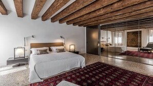Une chambre moderne avec un grand lit, des tables de chevet, un tapis rouge à motifs et un plafond en bois.