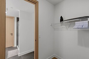 Una stanza con una porta in legno, un muro bianco e uno scaffale in metallo con asciugamani piegati.