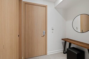 A room with a wooden door, a bench, a mirror, and a black object on the floor. - THE VALO Ostrya 3BDR Mont-Tremblant (Mont-Tremblant)