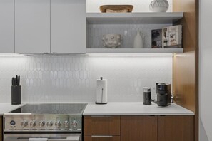 Una cucina moderna con piano cottura in acciaio inossidabile, ripiani bianchi e mobili in legno.