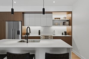 A modern kitchen with a central island, stainless steel appliances, and pendant lighting. - THE VALO Ostrya 3BDR Mont-Tremblant (Mont-Tremblant)