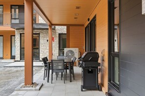 An outdoor patio with a table and chairs, a grill, and a fan. - THE VALO Ostrya 3BDR Mont-Tremblant (Mont-Tremblant)