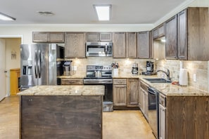 Una cocina moderna con electrodomésticos de acero inoxidable, armarios de madera y encimera de granito.