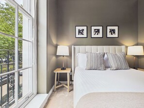 Ett hotellrum med en stor säng, två sänglampor, ett litet sidobord och tre inramade tavlor på väggen.