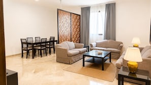 A modern living room with a dining area, two sofas, a coffee table, and a decorative partition. - WAY RESDINCE (Jeddah)