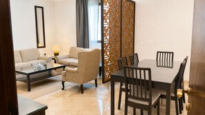 A living room with a sofa, coffee table, and a dining area with a table and chairs. - WAY RESDINCE (Jeddah)