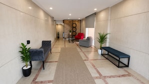 A hallway with a bench, a sofa, and a red chair. There are potted plants and a patterned wall. - WAY RESDINCE (Jeddah)