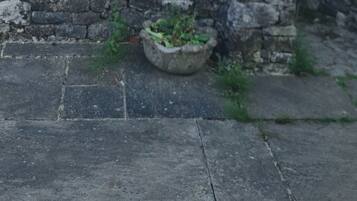 A stone wall, a concrete pathway, and a building with a tiled roof.