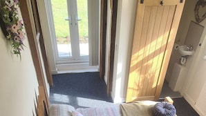 Ein Schlafzimmer mit einem Bett, Kissen, einem hölzernen Kopfteil, einem Fenster und einer Tür, die auf einen Balkon führt.