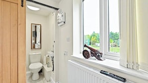 Ein Badezimmer mit Toilette, Heizkörper und einem Fenster mit Blick auf Grünflächen.