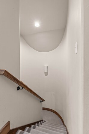 A narrow stairway with a wooden handrail and a white wall. - Eagle’s Rest – Your Mountain Getaway (Steamboat Springs)