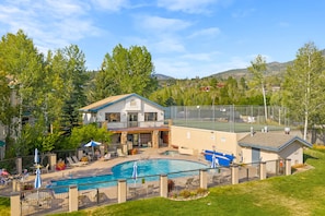 A residential property with a swimming pool, outdoor seating, and a tennis court. - Eagle’s Rest – Your Mountain Getaway (Steamboat Springs)