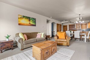 A living room with a sofa, armchair, coffee table, and a painting of a tree. - Eagle’s Rest – Your Mountain Getaway (Steamboat Springs)