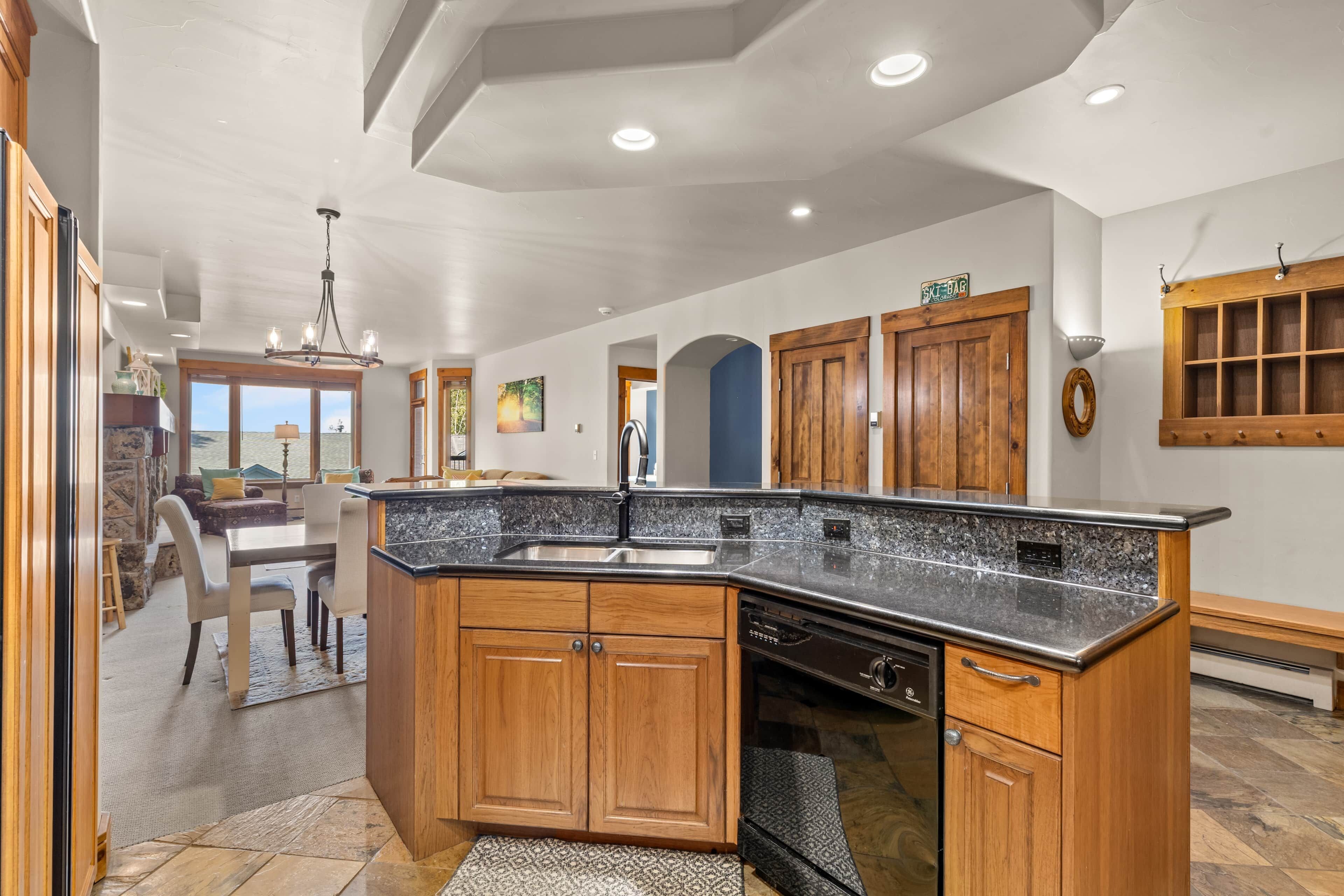 A modern kitchen with granite countertops, wooden cabinets, and a built-in dishwasher.