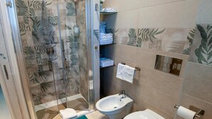 Une salle de bain comprenant une douche à parois de verre, des toilettes, un bidet et un lavabo.