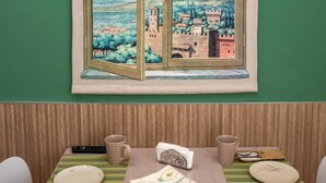 Un coin repas avec une table dressée pour deux personnes, une fenêtre donnant sur un paysage et un mur végétal.