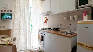 Une cuisine compacte équipée d’une cuisinière, d’un évier et d’un réfrigérateur. Un coin repas avec une table et des chaises est également prévu.