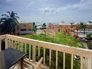 Un balcon donnant sur un quartier résidentiel, avec vue sur des maisons et une piscine.