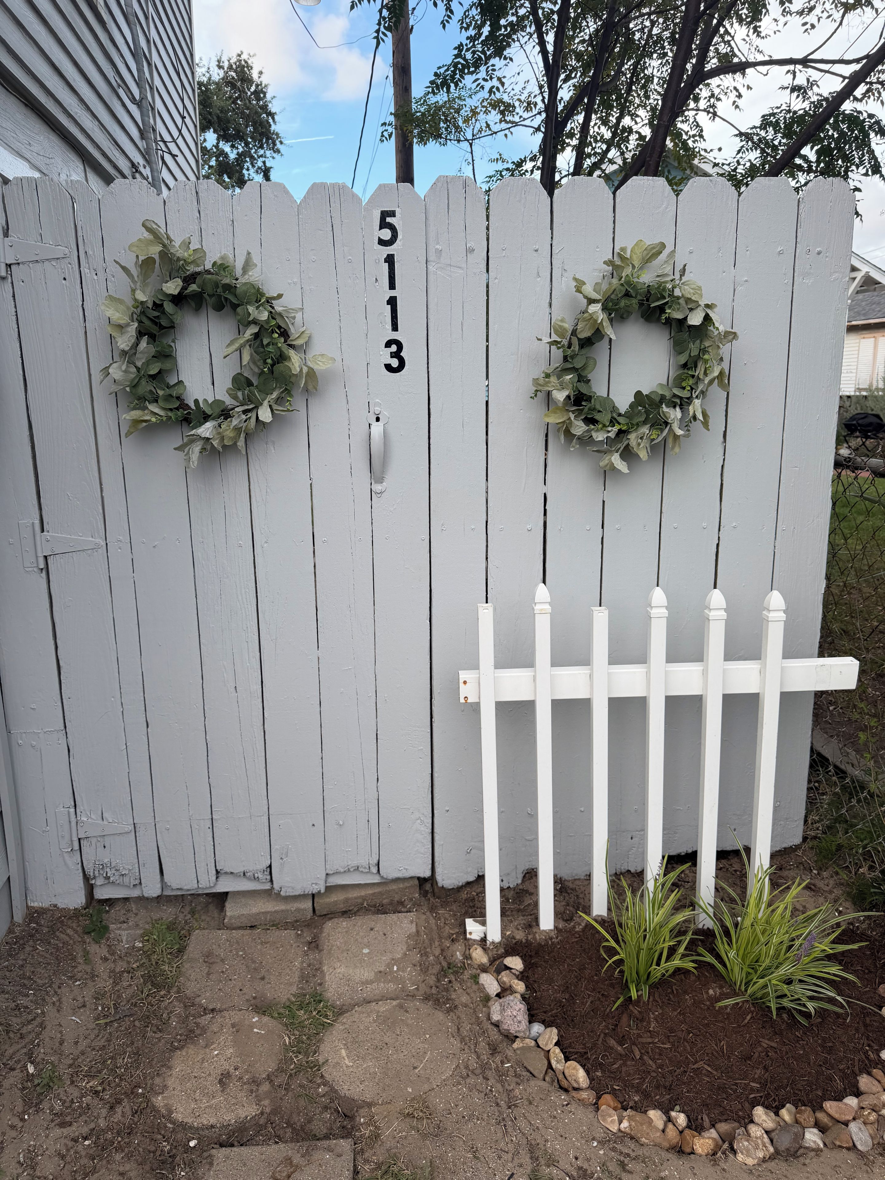 A white wooden fence with two wreaths and the number 513.