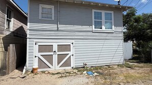 Una casa de dos pisos con garaje, antena parabólica y patio cercado.