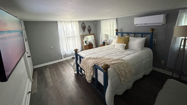 Un dormitorio con una cama, una mesita de noche, un espejo y una ventana con cortinas.
