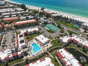 Ein Luftbild eines Resorts mit mehreren Gebäuden, einem Schwimmbad und einem Strand.