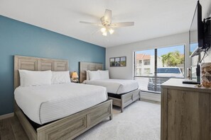 Ein Schlafzimmer mit zwei Betten, einem Deckenventilator, einem Schreibtisch mit Computer und einem Fenster mit Jalousien.